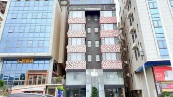 Un edifici de diverses plantes amb façana de vidre a l'esquerra i façana amb un disseny decoratiu a la dreta.