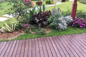 A wooden deck with a garden area featuring various plants and flowers. - Mossflower Hotel (Zhuhai Jinwan Airport) (Zhuhai)