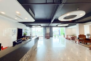 A modern hotel lobby with a marble reception desk, circular ceiling lights, and a view of the outdoors. - Mossflower Hotel (Zhuhai Jinwan Airport) (Zhuhai)
