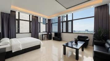 A modern hotel room with a large bed, a desk, a coffee table, and a sofa.