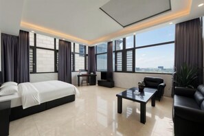 A modern hotel room with a large bed, a desk, a coffee table, and a sofa. - Mossflower Hotel (Zhuhai Jinwan Airport) (Zhuhai)