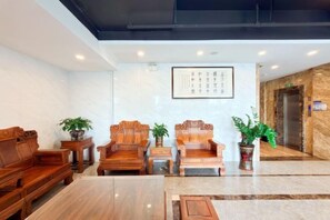 A lobby with wooden furniture, a marble floor, and a framed sign on the wall. - Mossflower Hotel (Zhuhai Jinwan Airport) (Zhuhai)