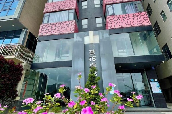 A modern building with a glass facade, a prominent sign with Chinese characters, and a balcony with a railing.