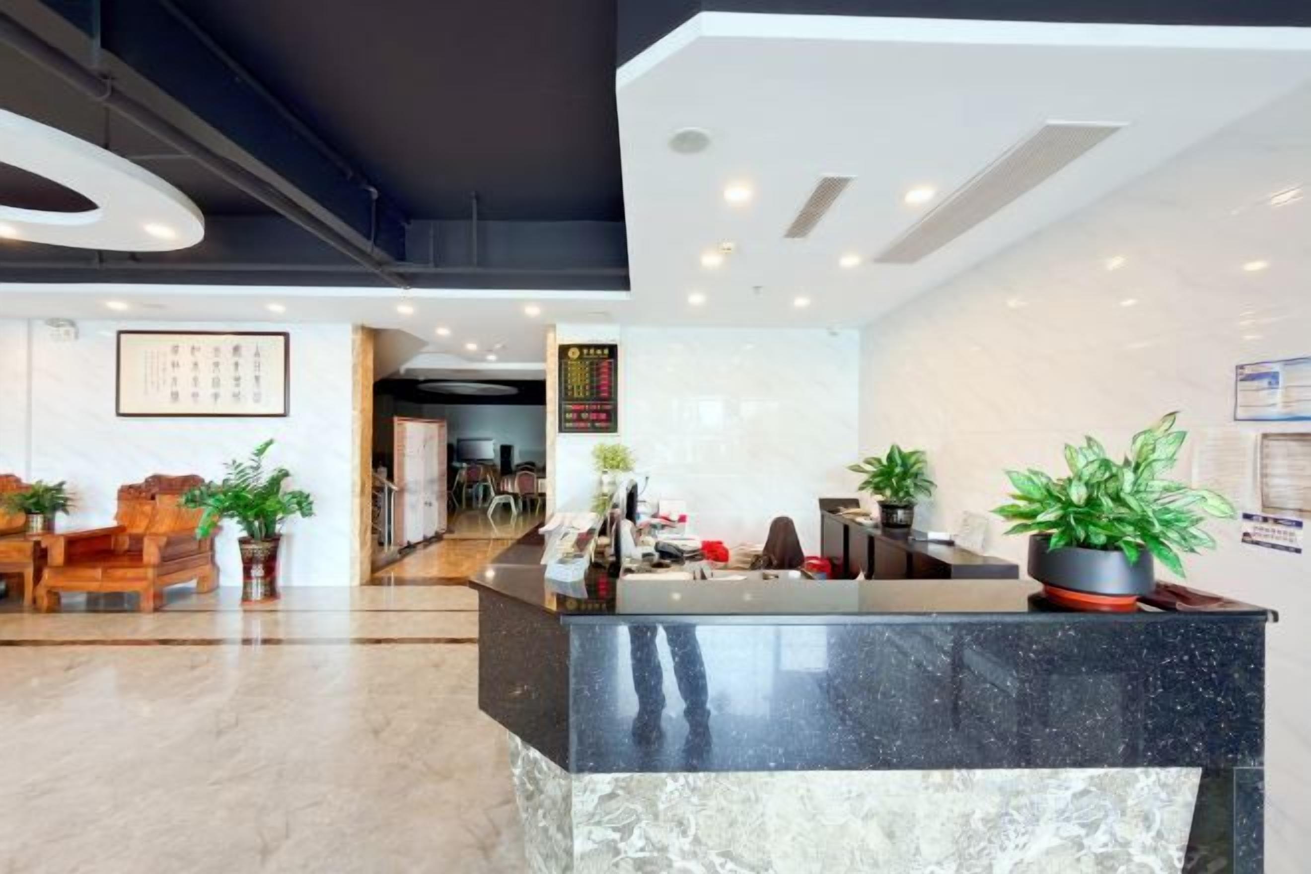 A hotel reception area with a marble counter, seating, and potted plants.
