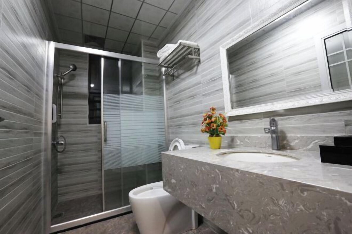 A modern bathroom with a glass-enclosed shower, a marble sink, and a potted plant.