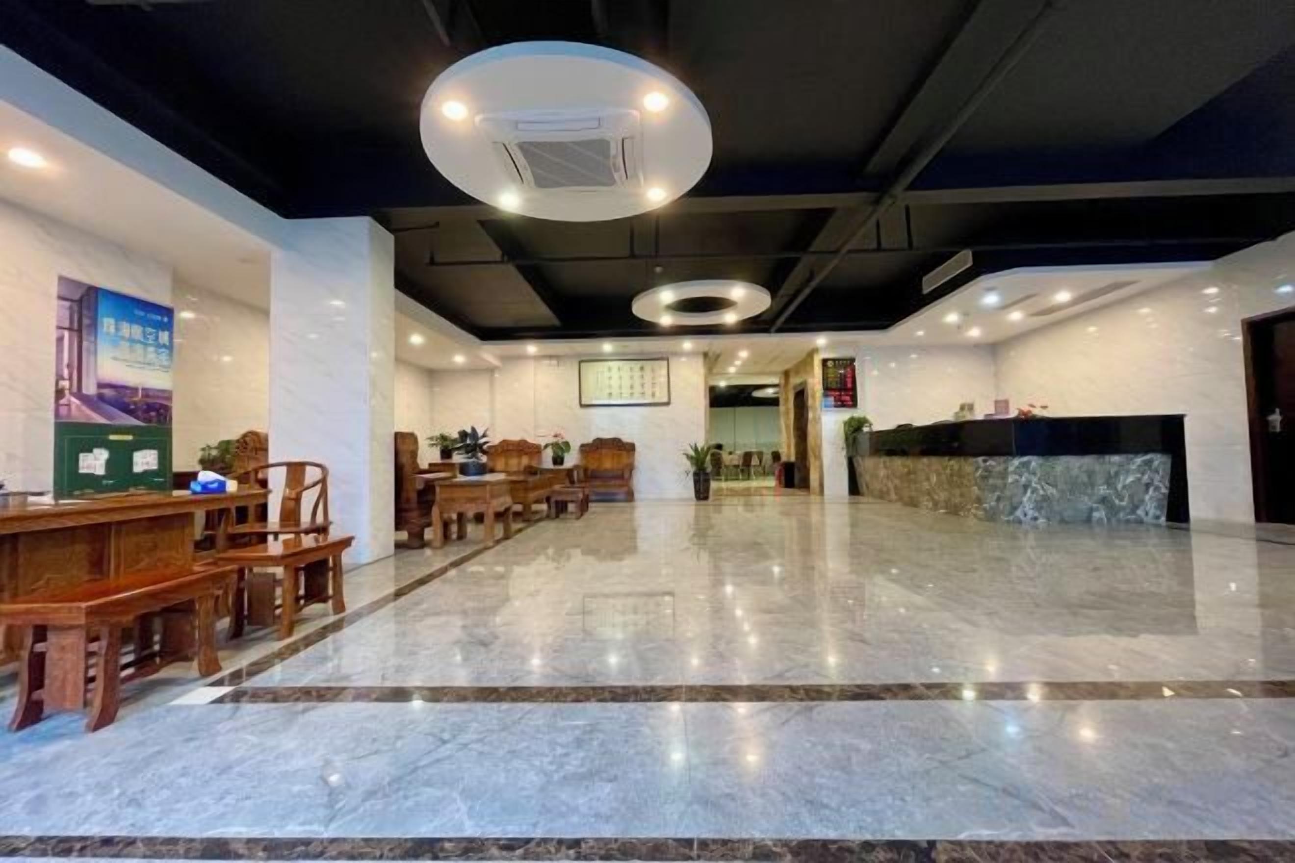 Een hotel lobby met een receptiebalie, een zithoek en een marmeren vloer.