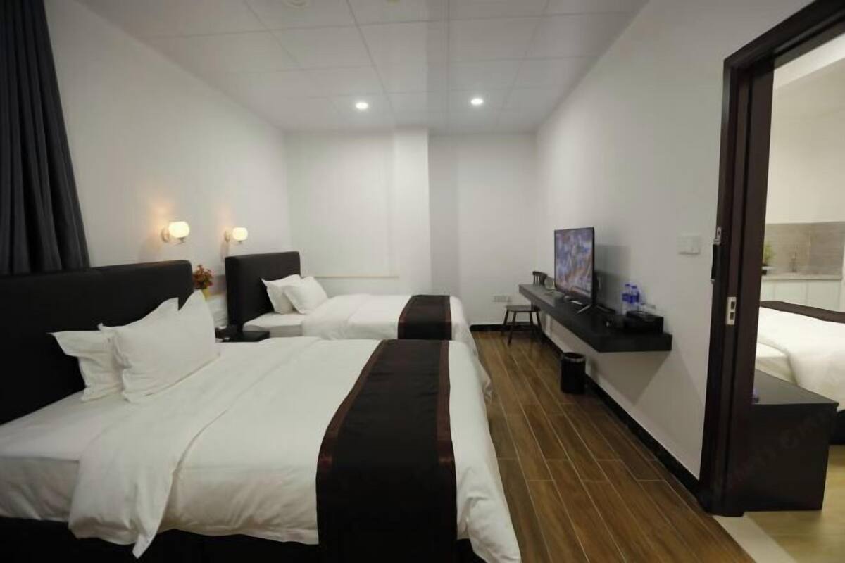 A hotel room with two beds, a flat-screen TV, a small table, and a door leading to a bathroom.