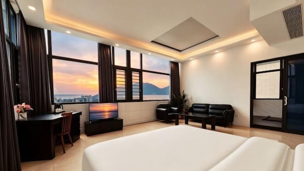 Habitación de hotel con una cama grande, un escritorio con silla, un sofá y un televisor.