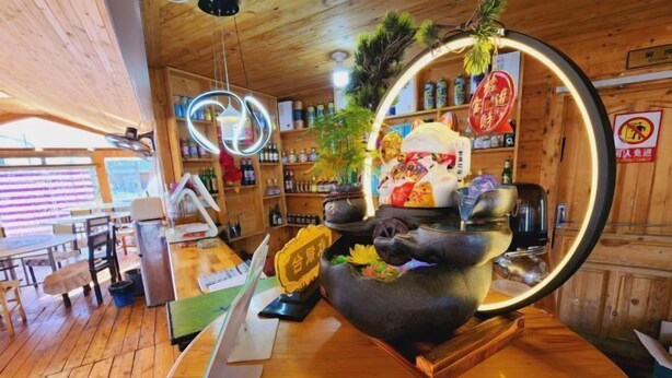 A restaurant interior with wooden walls, a central black table with a decorative item, and a counter with various items. - Ergune Enhe E Qing Moutain Villa (Ergun)