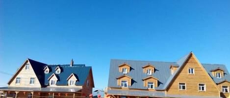 A row of wooden buildings with multiple stories and a flat roof design.