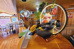 Interior de un restaurante con pisos de madera, una mesa negra central con un objeto decorativo y una lámpara circular colgante.