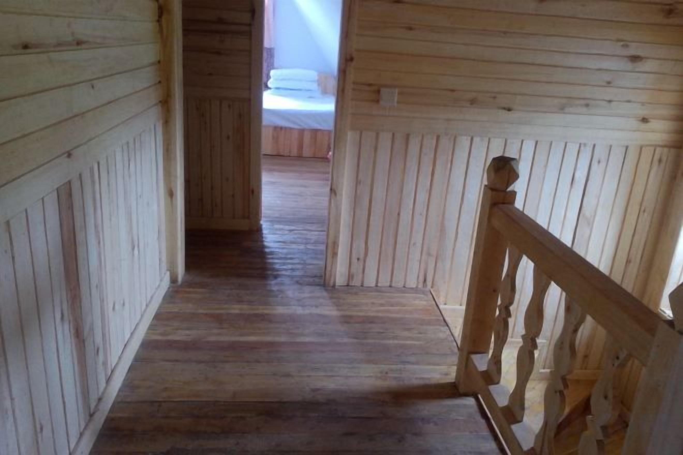 A wooden interior hallway with a wooden railing on the right.
