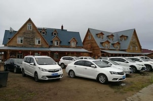 Uma fileira de carros brancos estacionados em frente a uma fileira de edifícios de madeira com telhados inclinados.