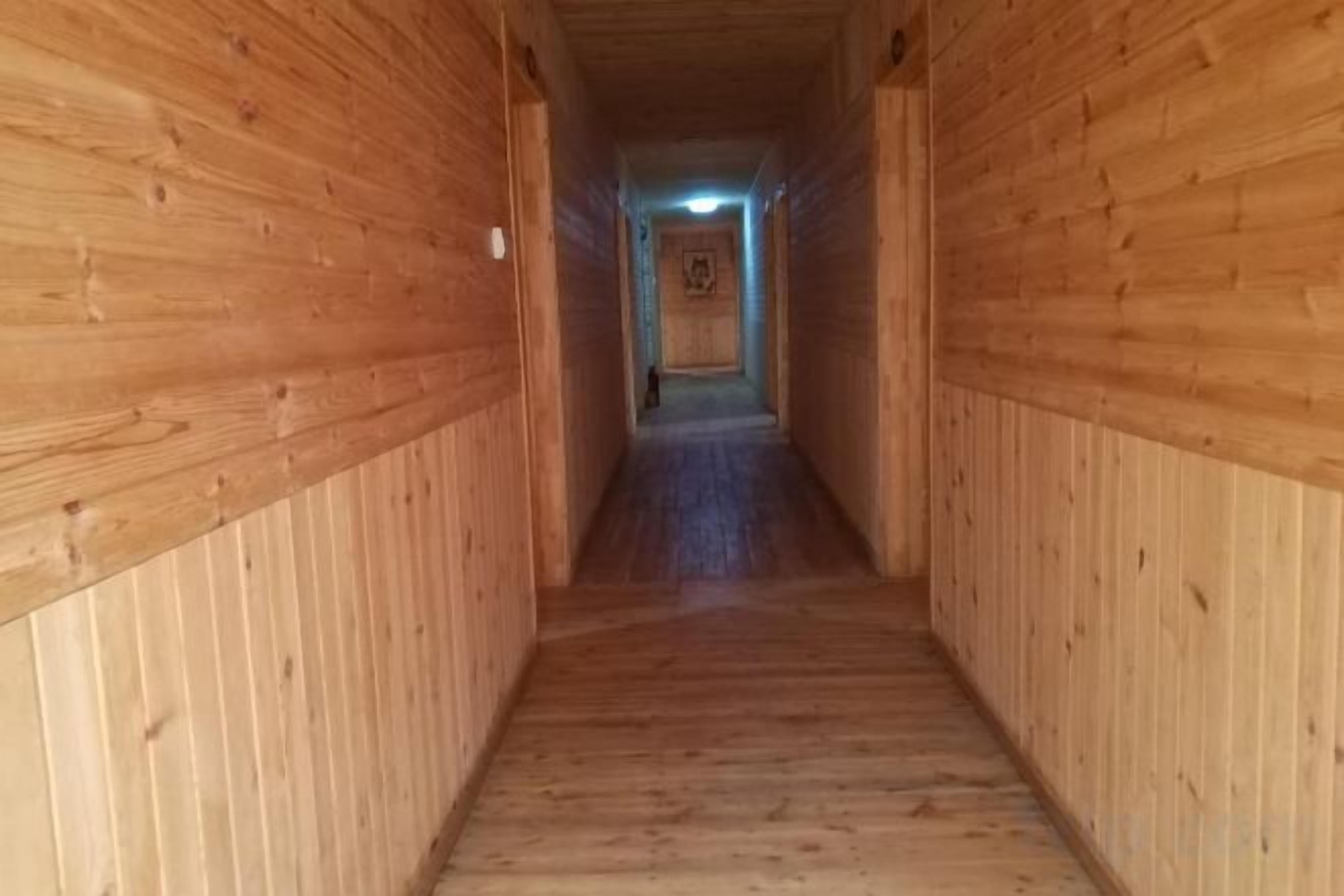 Un couloir en bois avec une porte au bout.