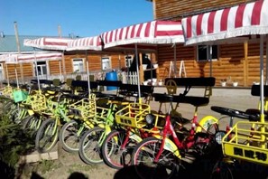 A row of bicycles parked under striped awnings, a wooden building with a porch, and outdoor seating. - Ergune Enhe E Qing Moutain Villa (Ergun)