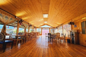 A wooden interior with tables and chairs arranged for dining.