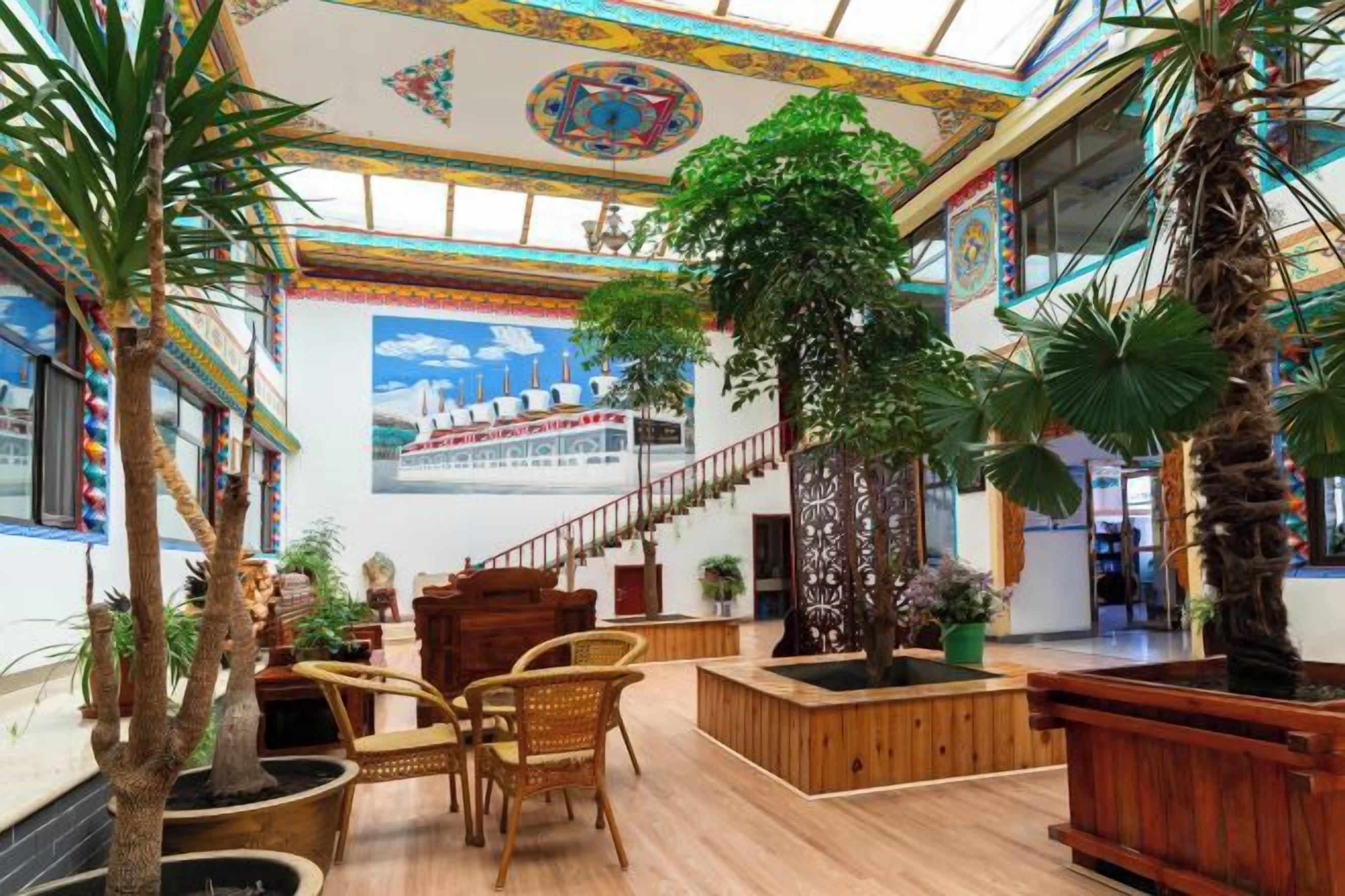 Eine großzügige Lobby mit hoher Decke, einer Treppe und mehreren Kübelpflanzen.