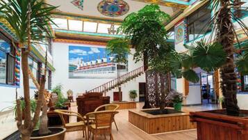 Eine großzügige Lobby mit hoher Decke, einer Treppe und mehreren Kübelpflanzen.