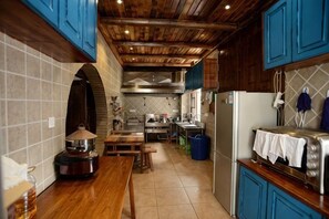 A kitchen with wooden cabinets, a tiled backsplash, and a stainless steel refrigerator. - Huayutang Renwen Inn (Luoping)