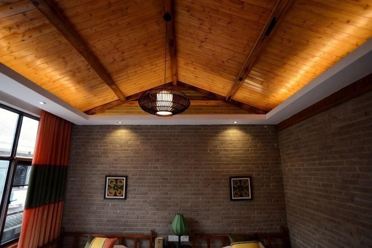 A room with a wooden ceiling, brick walls, and a hanging light fixture.