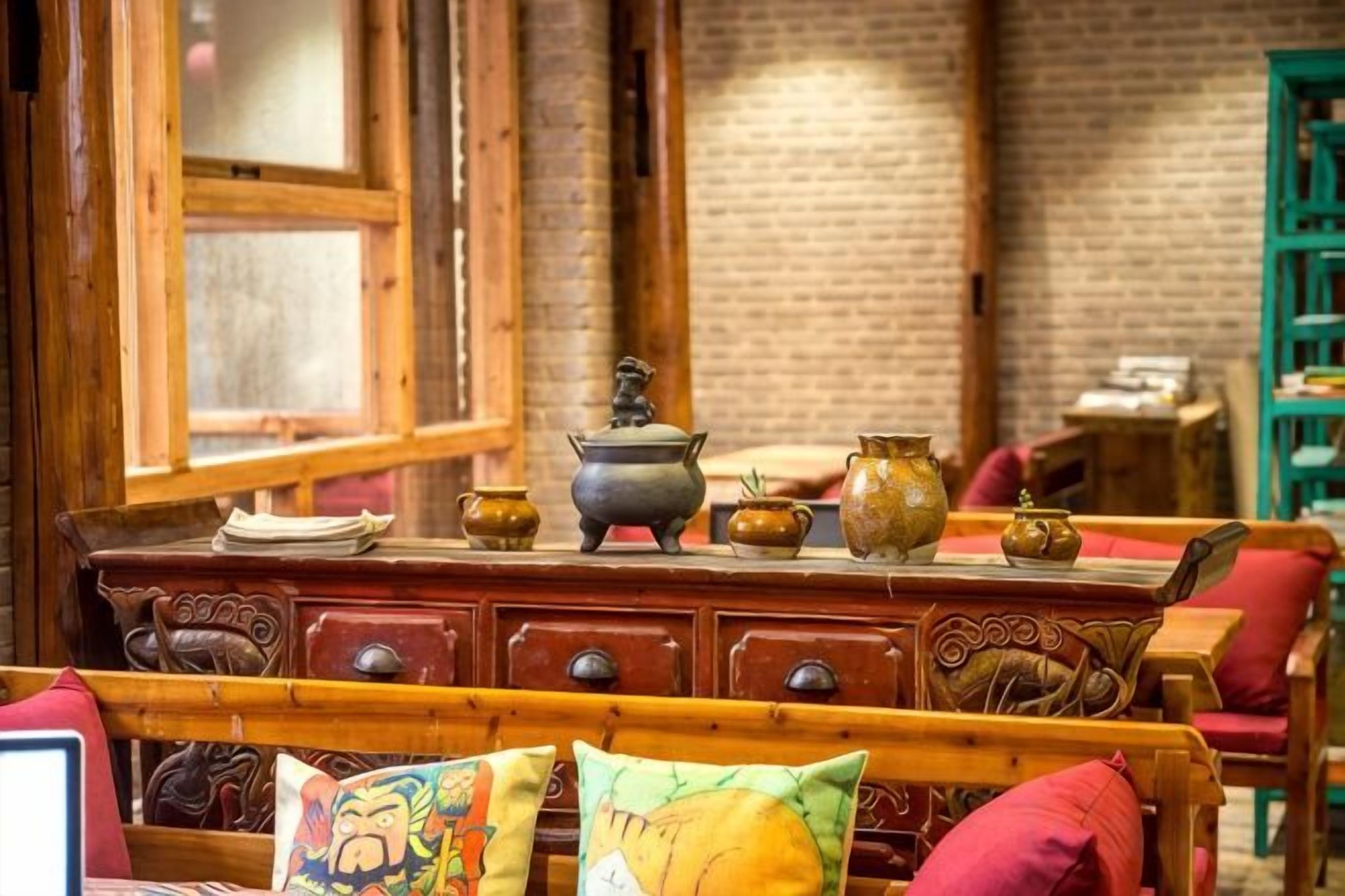 A room with a wooden bed, a dresser with decorative items, and a brick wall.