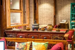 Una habitación con una cama de madera, un aparador con adornos y una pared de ladrillo.