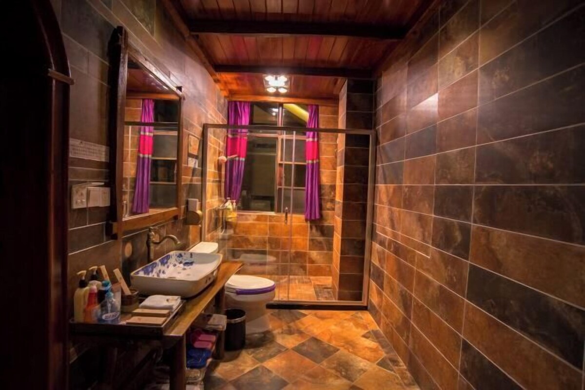 A bathroom with a wooden ceiling, a sink, a toilet, and a shower area.