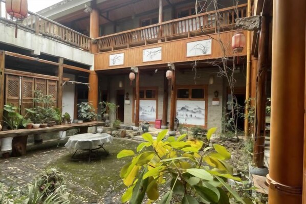 A traditional courtyard with a wooden balcony, potted plants, and a small water feature. - Huayutang Renwen Inn (Luoping)