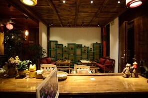 A cozy interior with wooden furniture, a green bookshelf, and a wooden ceiling. - Huayutang Renwen Inn (Luoping)