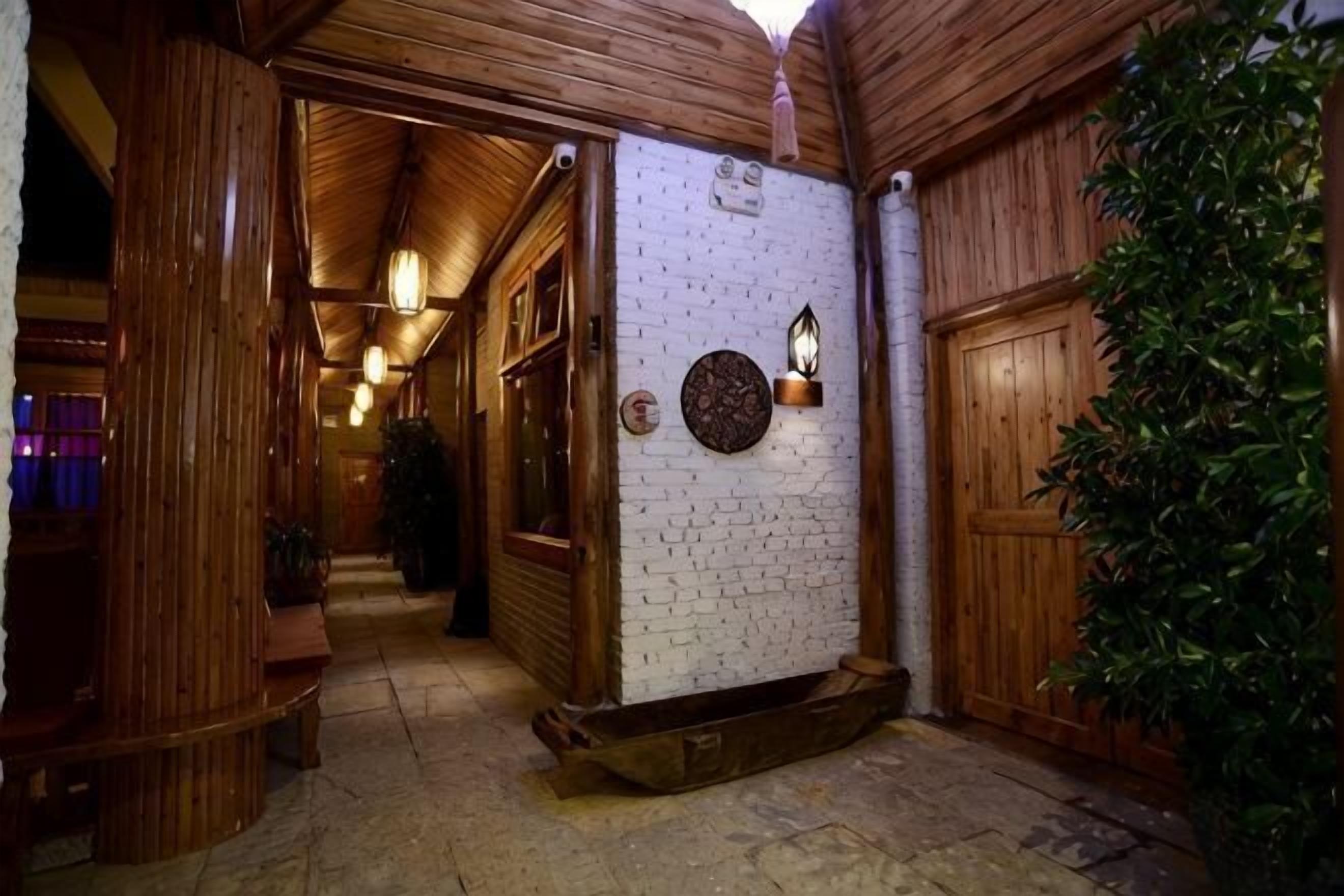 A wooden interior hallway with a brick wall, wooden door, and a potted plant.