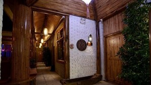 A wooden interior hallway with a brick wall, wooden door, and a potted plant. - Huayutang Renwen Inn (Luoping)