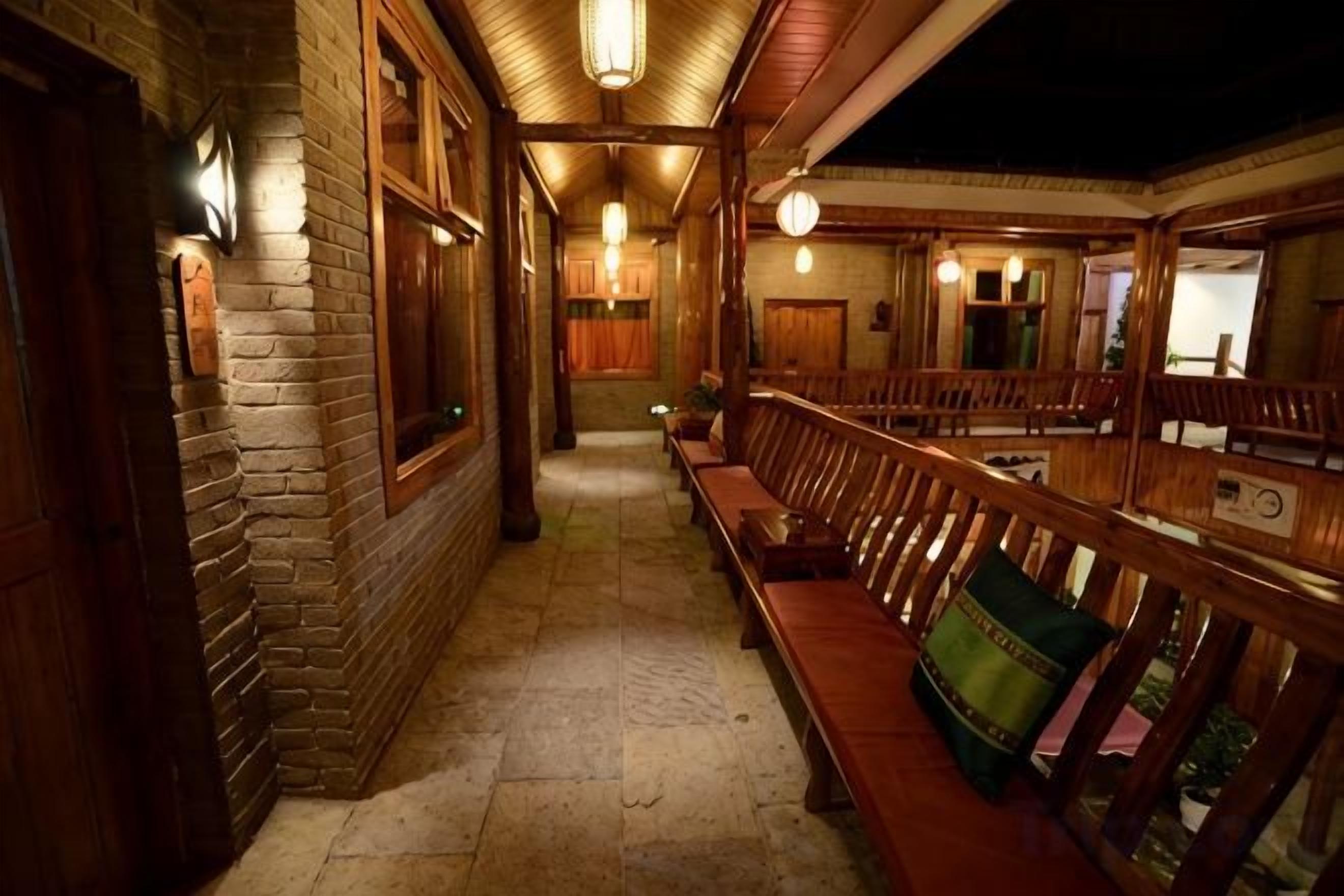 A corridor with benches and wooden railings, leading to a room with a window.