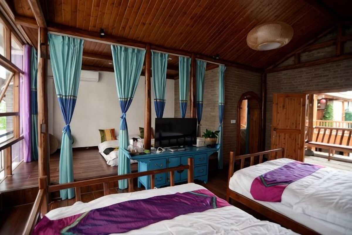 A room with two beds, a TV, a desk, and curtains.