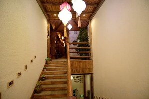 A wooden staircase with a railing, potted plants, and hanging lights. - Huayutang Renwen Inn (Luoping)