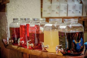 A row of glass jars with liquid contents, each with a tap, on a wooden shelf.