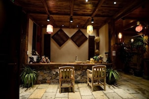 Una zona de bar con sillas de madera, una barra de piedra y faroles colgantes.