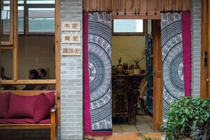 Un interior tradicional con una puerta de madera, un banco acolchado y un tapiz estampado.