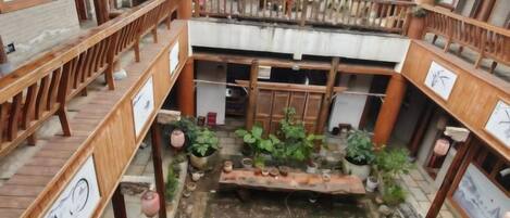 A traditional courtyard with wooden railings, a central water feature, and potted plants.