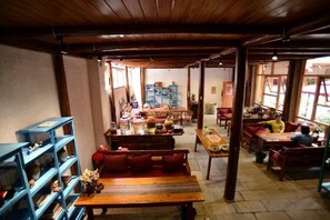 A cozy interior with wooden furniture, a central table, and a blue shelving unit. - Huayutang Renwen Inn (Luoping)