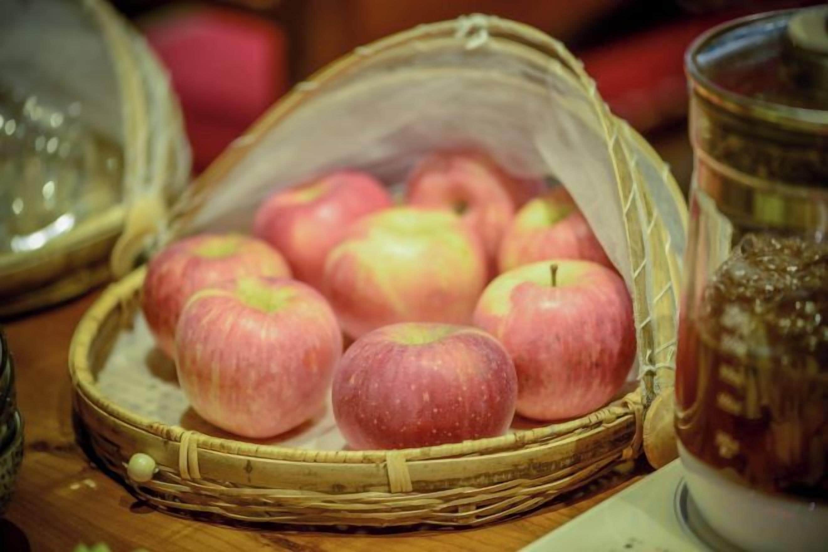 A basket of apples on a wooden surface.