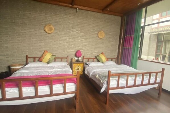A room with two wooden beds, a brick wall, and a window with curtains. - Huayutang Renwen Inn (Luoping)