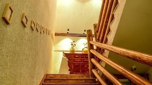 Eine Holzt Treppe mit Handlauf, eine Wand mit gerahmten Bildern und ein Holzschrank mit einer Vase.
