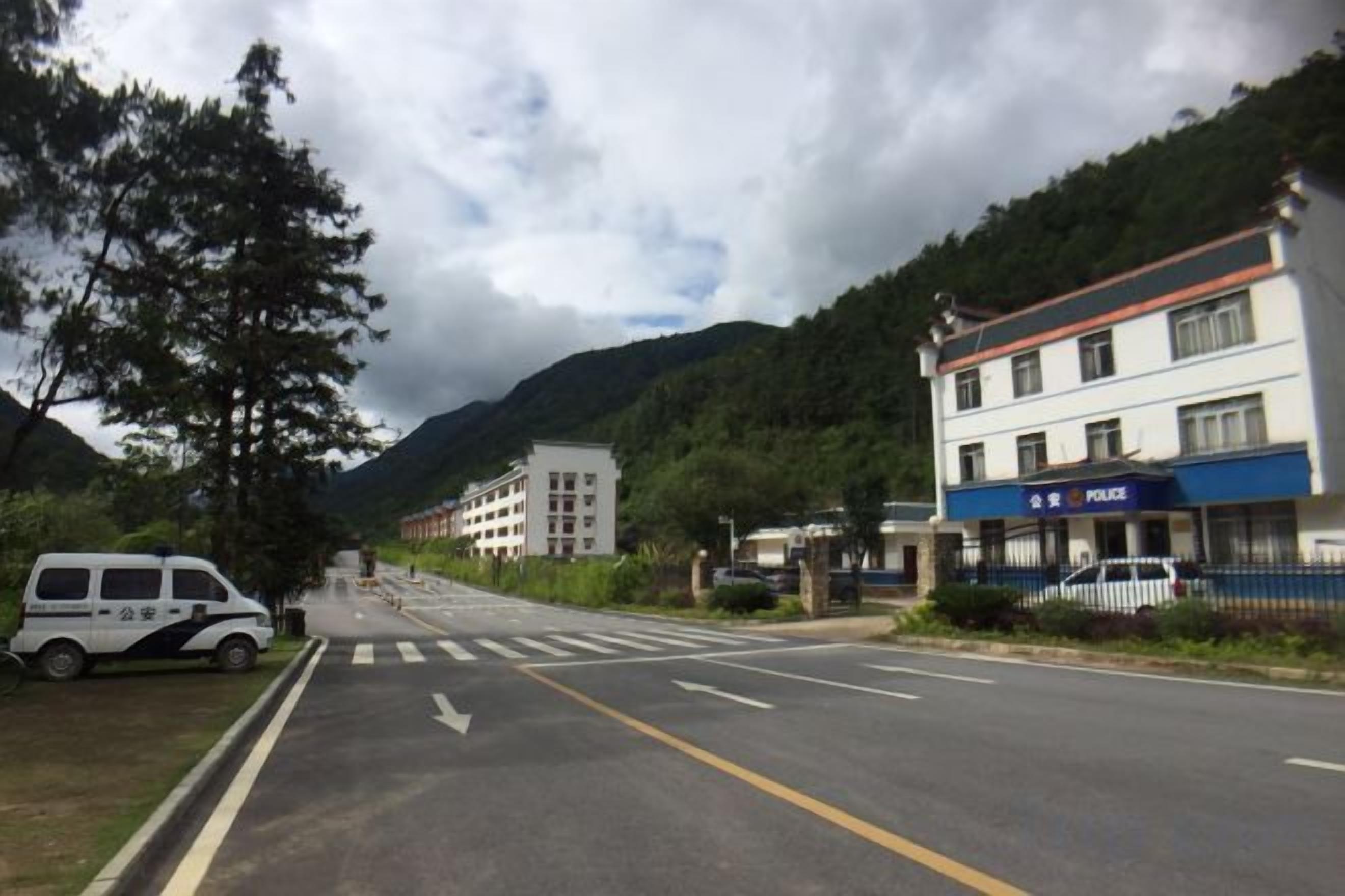 A street with a police station, a white van, and a building with a blue sign.