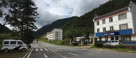 A street with a police station, a white van, and a building with a blue sign.
