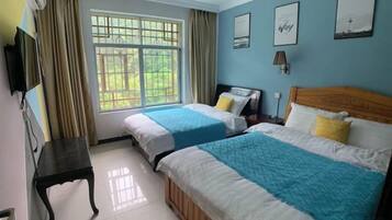 Una habitación de hotel con dos camas, televisión, ventana con cortinas y cuadros en la pared.