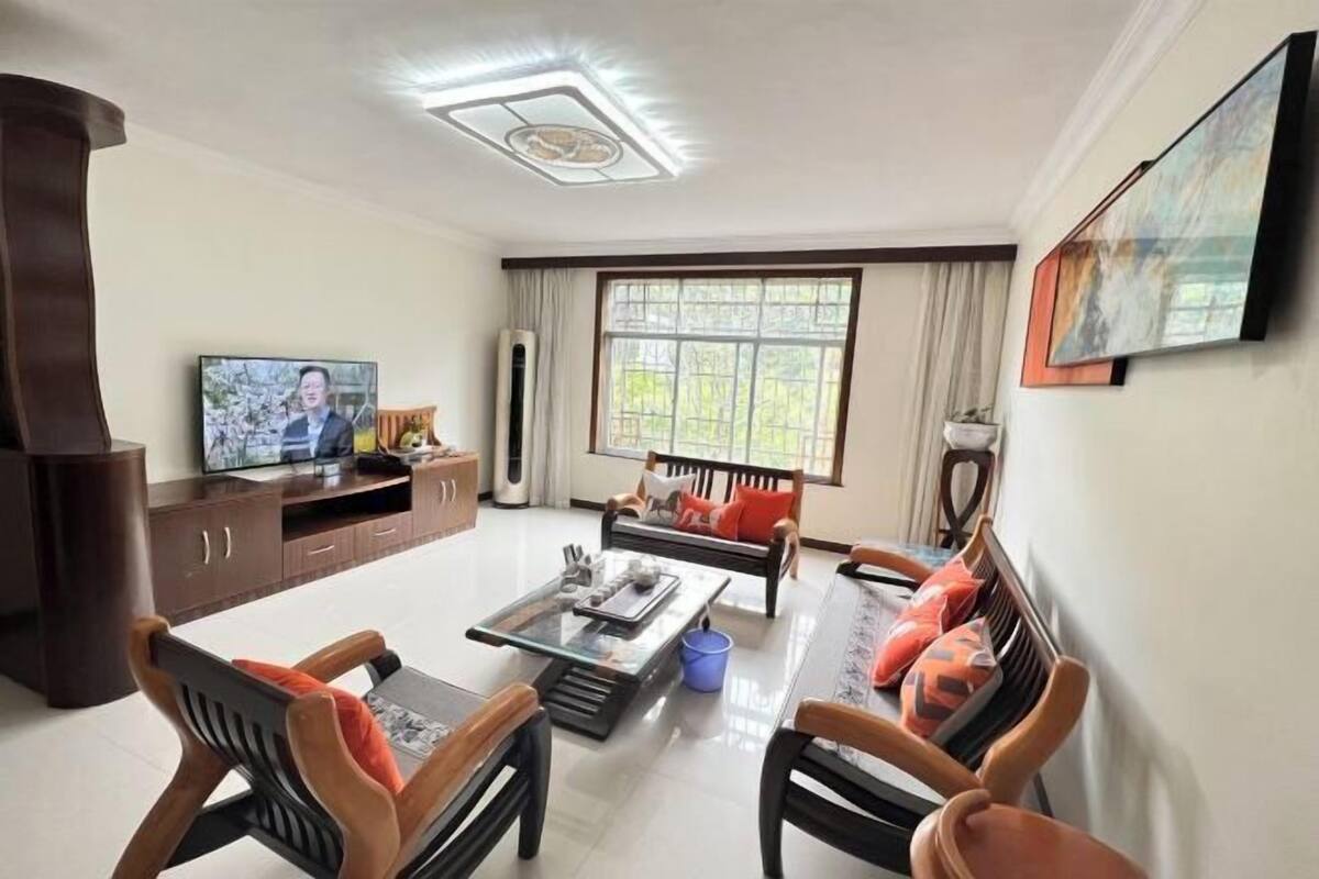 A living room with a sofa, coffee table, TV, and a large window.