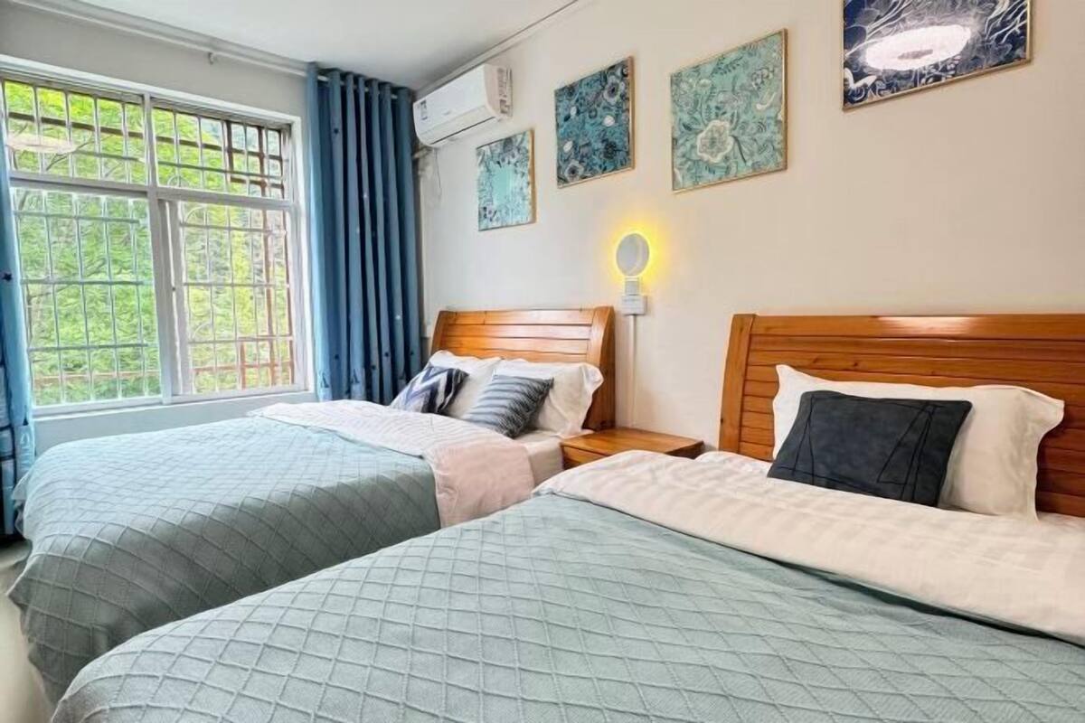 A hotel room with two beds, a window with curtains, and wall art.