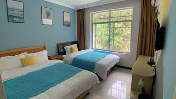 Habitación de hotel con dos camas, una ventana con cortinas, una mesita de noche y un televisor montado en la pared.