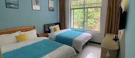 A hotel room with two beds, a window with curtains, a bedside table, and a wall-mounted TV.