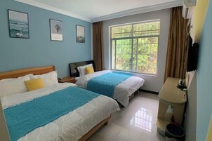 Habitación de hotel con dos camas, una ventana con cortinas, una mesita de noche y un televisor montado en la pared.